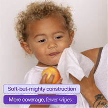 Baby smiling with a fruit while a caregiver holds wipes, soft and gentle coverage