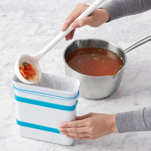 Freezer food block maker mold with blue band on counter next to pot with chopped ingredients