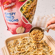 Baked casserole topped with crispy fried onions, spoon lifting onions