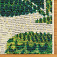 Indoor/outdoor rug close-up texture with green leaf block pattern on cream ground.