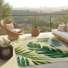 Indoor/outdoor rug with green tropical leaf pattern on light cream ground.