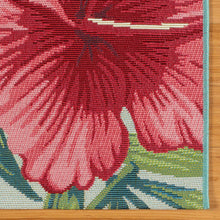 Indoor/outdoor rug detail: pink flower with green leaves and teal border edge