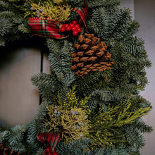 Fresh 22-inch noble fir mixed wreath close-up with pinecones, berries, red ribbon