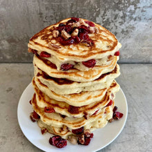 Stack of pancakes topped with cranberry and pecans.