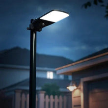 Solar area light on black pole with rectangular LED head glowing white at night