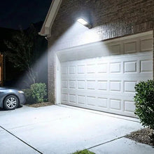 Solar motion area light mounted beside garage door, bright white flood illumination