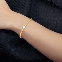 Freshwater pearl bracelet on wrist, cream-gold beads with central white pearl and gold clasp