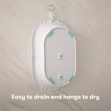 Hanging white sling insert with teal support pads for baby tub