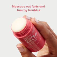 Open red Gassy Belly Rub container with white cream on lid, held by hands