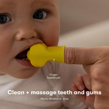 Yellow finger toothbrush with baby brushing on gums and teeth