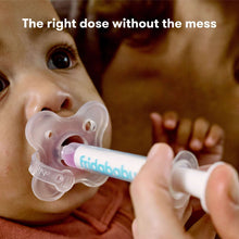 Baby receiving medicine with pacifier dispenser syringe held by hand