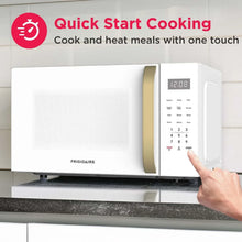 Countertop microwave with gold handle; finger pressing keypad start button