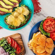 Assorted potato chips in two bowls with tomato and greens