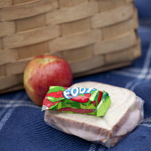 Fruit strip snack wrapped on a loaf of bread with an apple on a blue surface