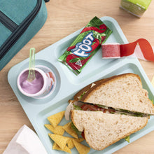 Fruit strip snack pieces and wrapper on a white tray with sandwich and chips