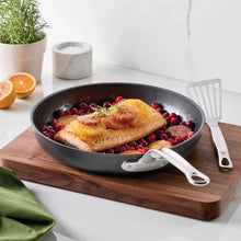 Nonstick skillet holding cooked fish and berries; dark interior and long stainless handle