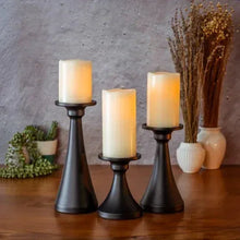 Matte black candle holders with three cream pillar candles, tabletop display