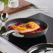 Nonstick skillet with long stainless handle, containing cooked fish and berries