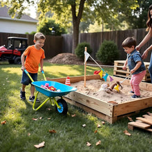 Kids metal wheelbarrow with blue tub and green frame near a sandbox