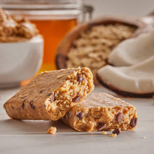 Chocolate chip protein bars, two broken pieces with dark chocolate bits on a light surface