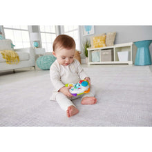 Musical learning controller toy held by baby on a living room floor