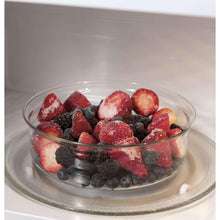 GE countertop microwave oven with glass turntable dish of frozen berries inside
