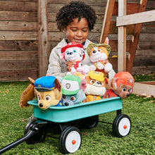 Firefighter dog plush toy in red uniform, held among other character plush figures in wagon