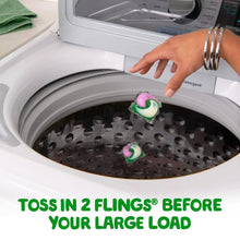 Laundry detergent flings being placed into a top-load washing machine drum