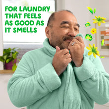 Man in a mint green robe holding his hands near his face with flower icons