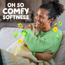 Smiling woman hugging cushions on a couch with yellow flower graphics
