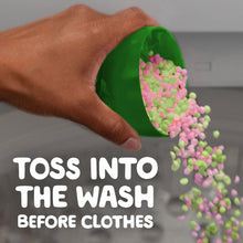 Green laundry scent booster beads bottle tipping pink beads into a hand