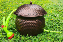 Dark copper hammered hose storage pot with domed lid and attached garden hose