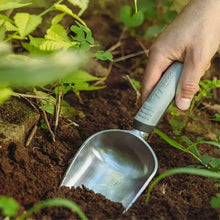 Small steel trowel with gray grip in dark garden soil