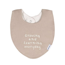 Taupe baby bib with snap and text reading "GROWING AND LEARNING EVERYDAY"