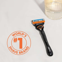 Manual razor with black handle and orange 5-blade cartridge on white surface