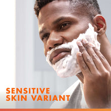 Man applying white shaving foam with a shaving razor near his cheek