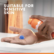 Orange shave gel can dispensing a blue gel drop onto open palm