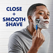 Man shaving with blue-handled Gillette razor