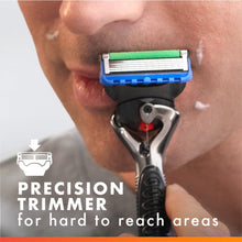 Razor with precision trimmer cutting through foam on cheek, blue cartridge.