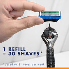 Razor refill blade cartridge lifted by hand, blue base with green strip.