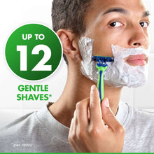 Handheld disposable razor with shaving cream on man's cheek, green and blue handle