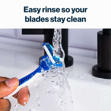Disposable razor rinsed under water, blue cartridge and white handle.