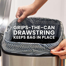 Gray kitchen trash bag with drawstring grip on trash can rim.
