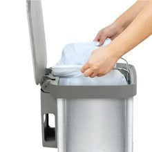 Stainless steel step trash can with swing lid open as hands load a liner