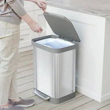 Stainless steel step trash can with lid open and pedal base, liner being placed