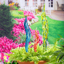 Set of 3 glass garden stakes with blue, red, and yellow swirled tops in a planter.