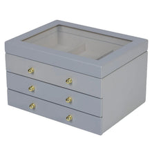 Gray lift-top jewelry box with open lid, three drawers, and gold round knobs on front