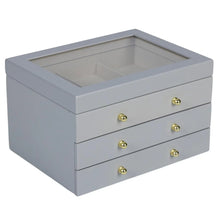 Gray lift-top jewelry box with open top, three drawer fronts, and gold round knobs