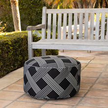Round pouf with black fabric and white grid stripe pattern, cushioned top