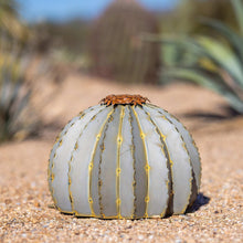 Outdoor torch sculpture with ribbed white barrel and gold accents, rusted floral top